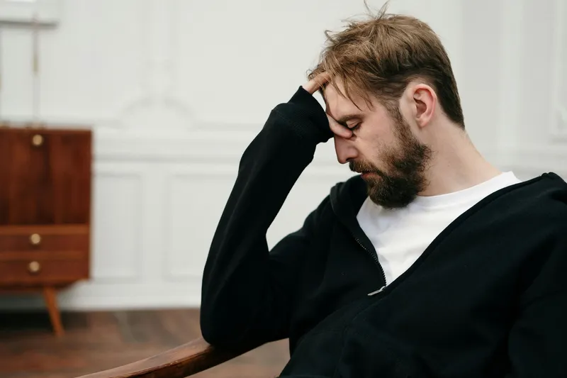 A stressed man holding his head